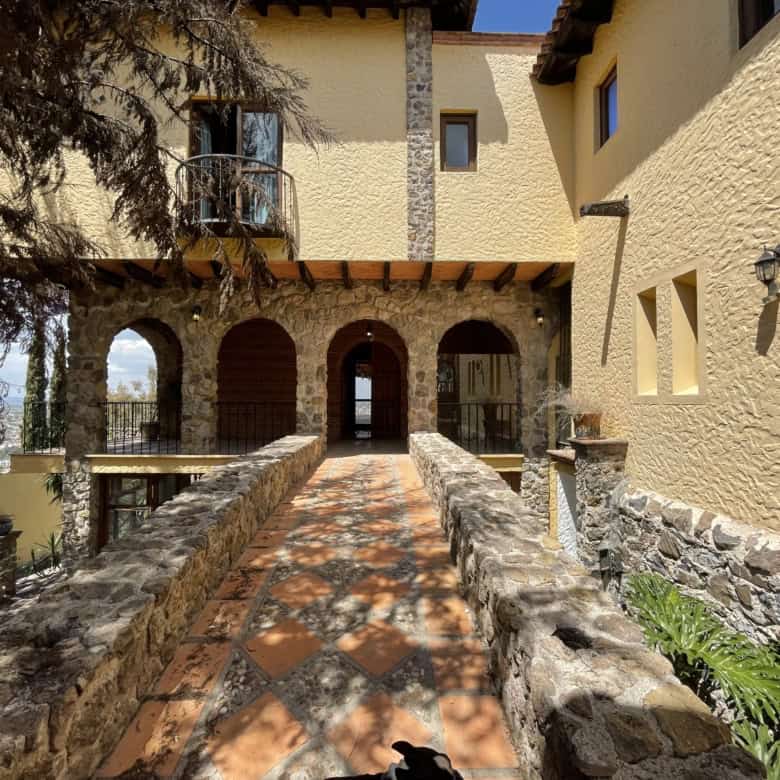 Elegant villa entrance with stone pathway and lush greenery.