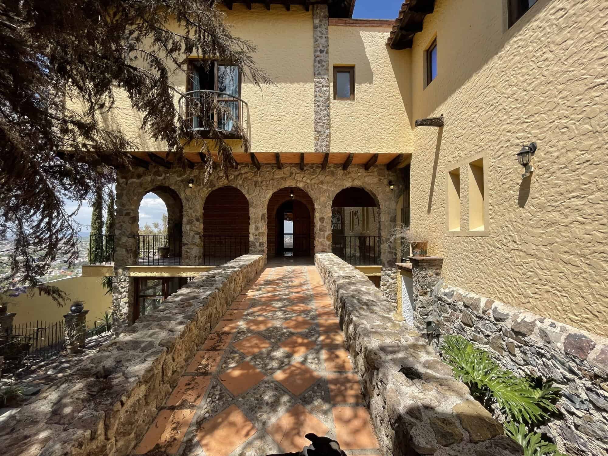 Elegant villa entrance with stone pathway and lush greenery.