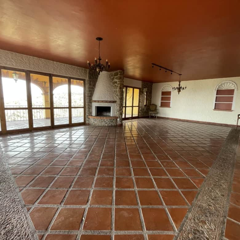 Bright and airy living room featuring a cozy fireplace, expansive windows, and terracotta tiled floo.