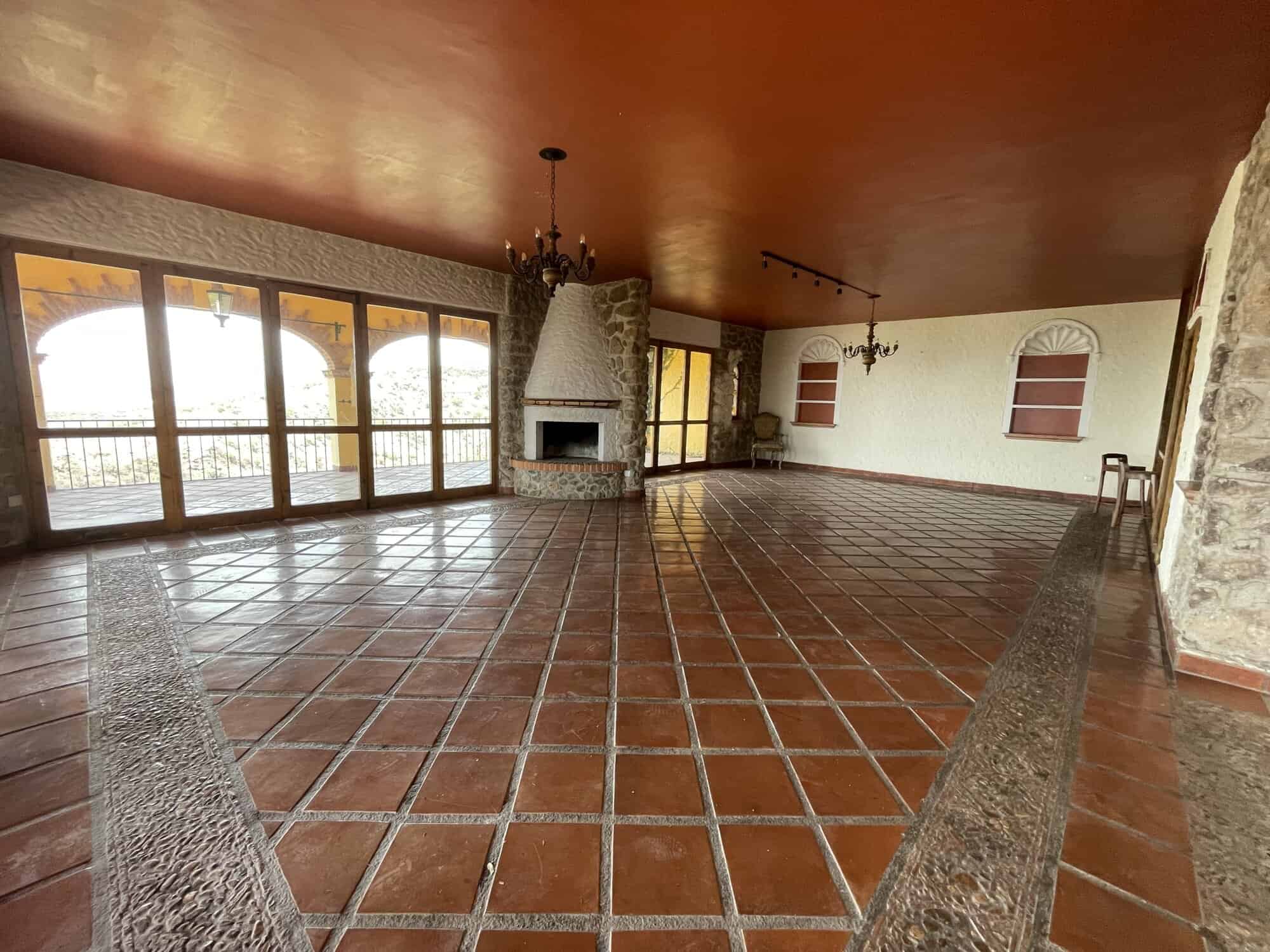 Bright and airy living room featuring a cozy fireplace, expansive windows, and terracotta tiled floo.