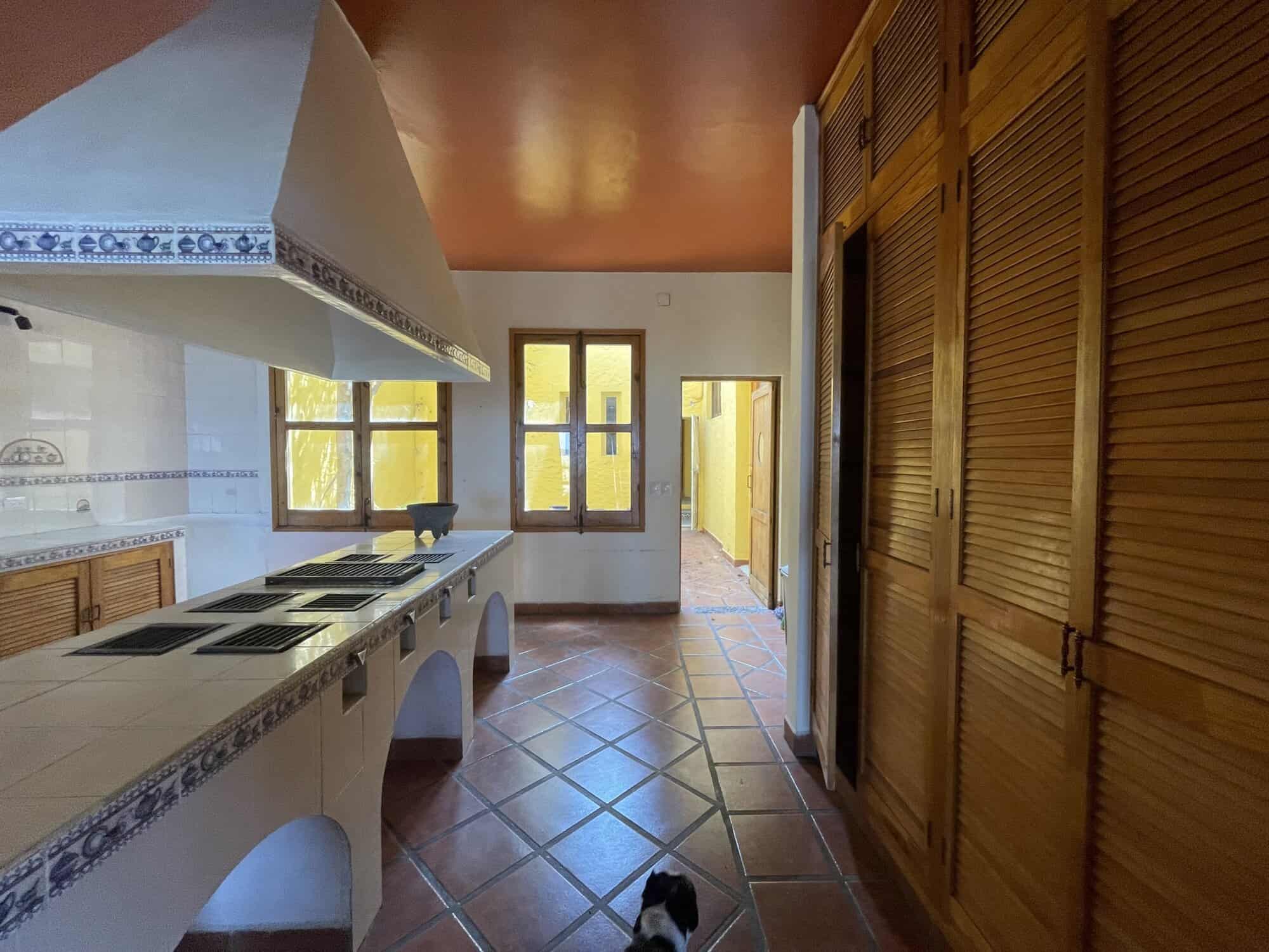 Warm kitchen with wooden cabinets and terracotta tiles.