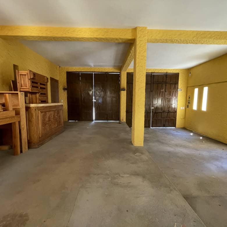 Interior of a bright yellow room with wooden furniture and large dark doors.