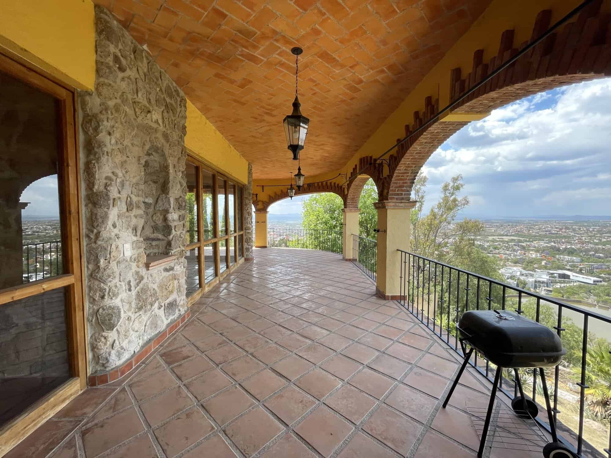 Luxury villa balcony overlooking scenic landscape and city views.