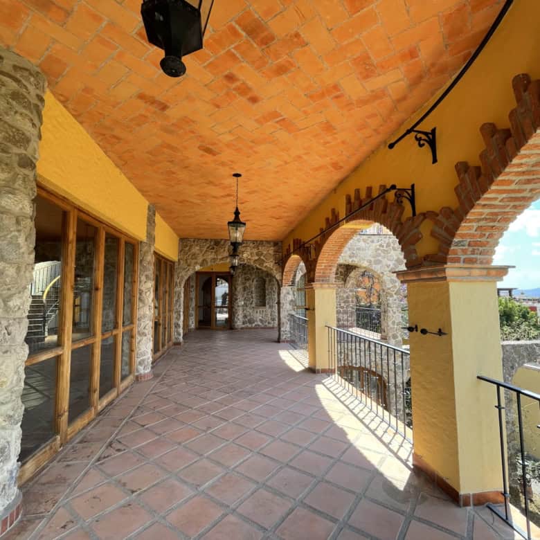 Balcony of a Spanish villa with stone arches and terracotta tiles, offering scenic views and outdoor.
