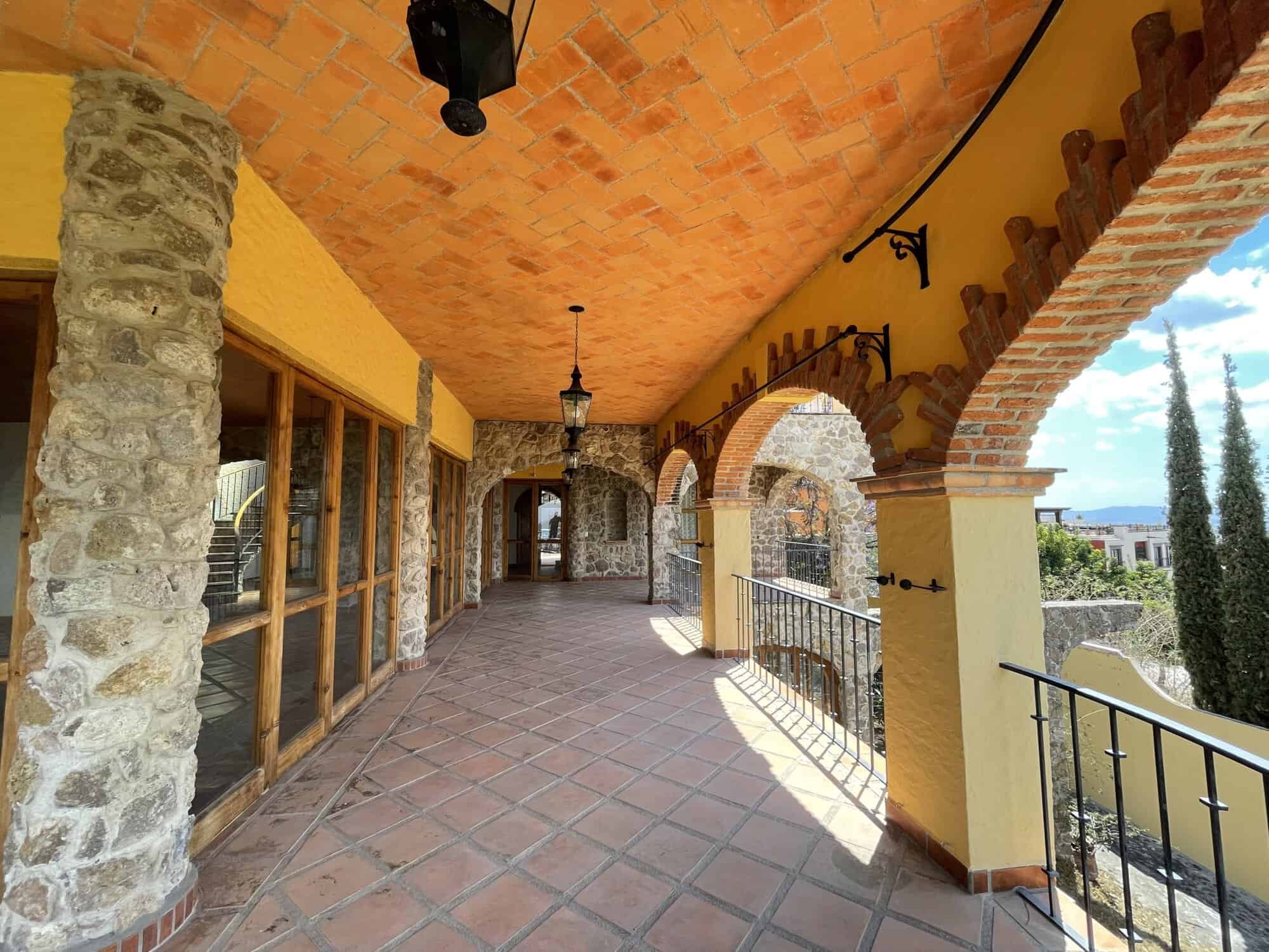 Balcony of a Spanish villa with stone arches and terracotta tiles, offering scenic views and outdoor.