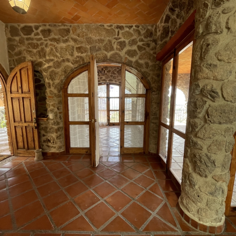 Stone-walled sunroom with large windows and terracotta tiled floor for relaxing and enjoying natural.