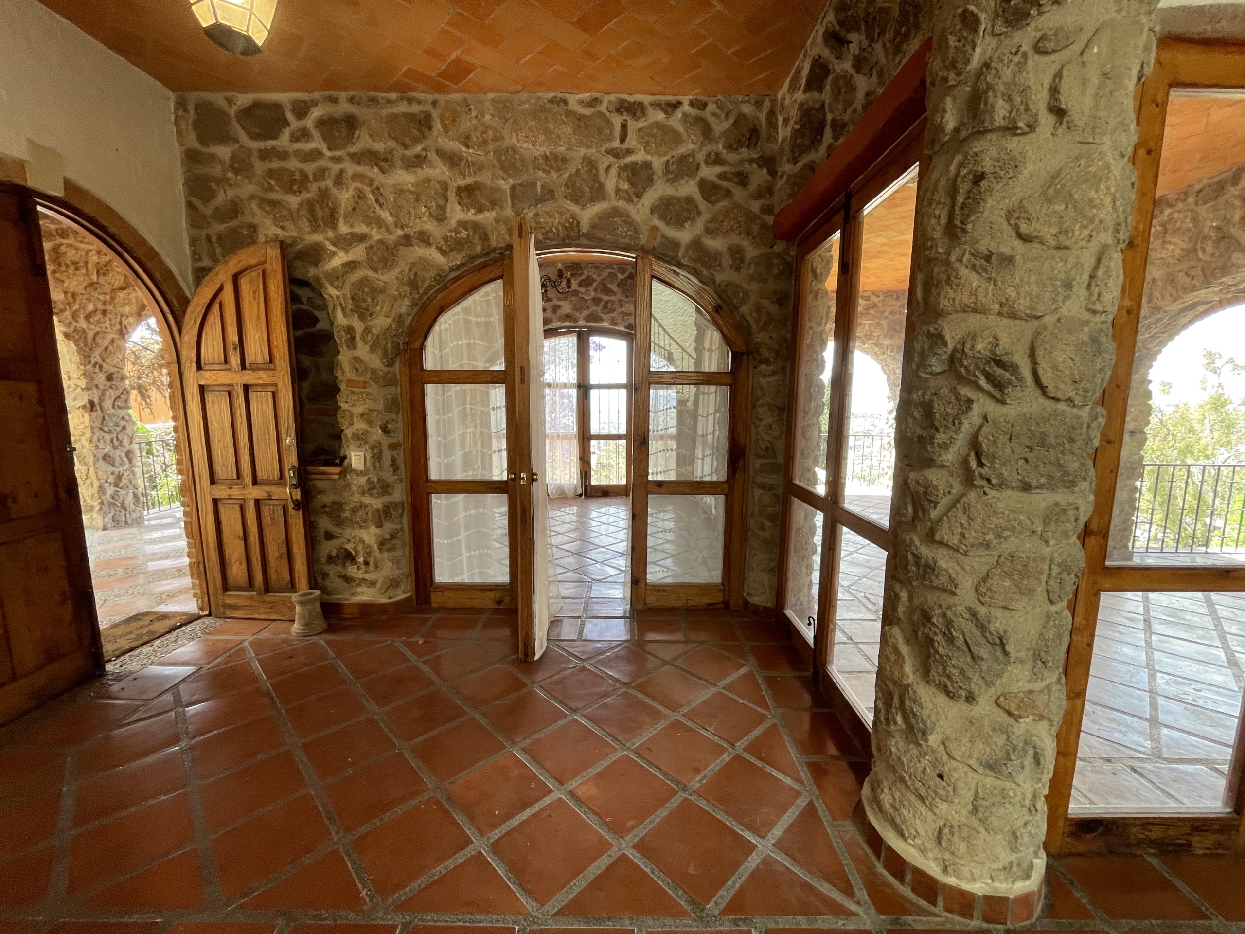 Stone-walled sunroom with large windows and terracotta tiled floor for relaxing and enjoying natural.