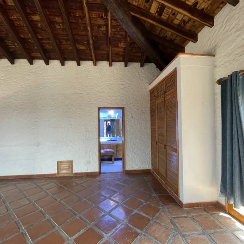Beachfront villa living room with rustic wooden ceiling and terracotta tiled floor.