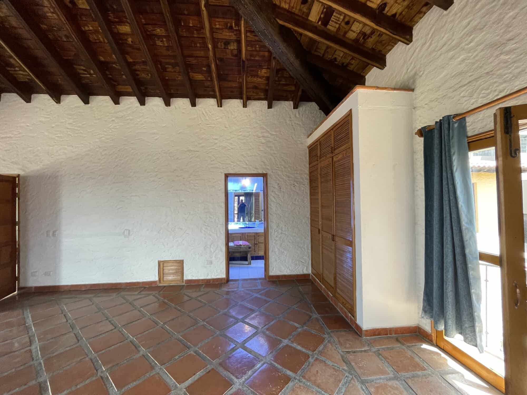 Beachfront villa living room with rustic wooden ceiling and terracotta tiled floor.