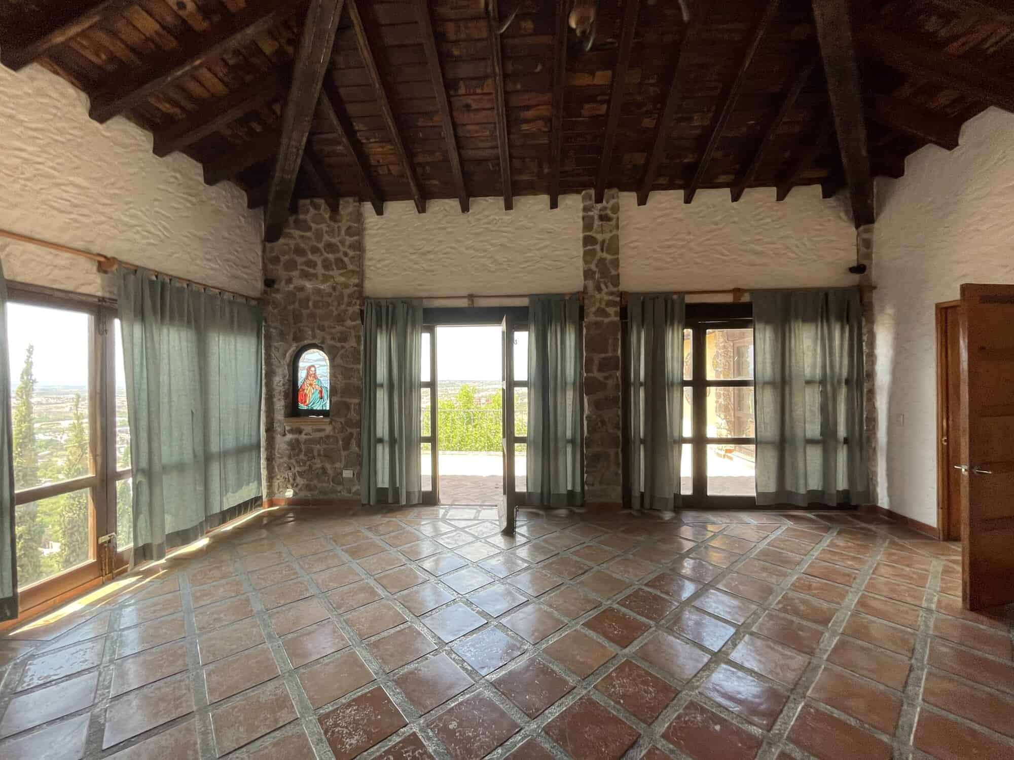 Luxury living room with stone walls, large windows, and wooden ceiling beams. Bright, spacious inter.