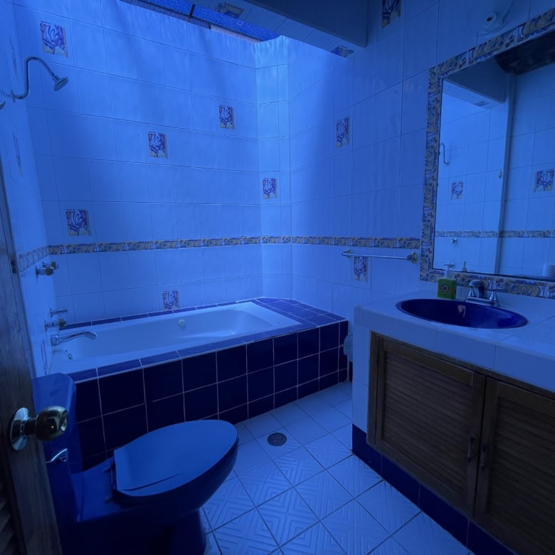 Blue-tiled bathroom with bathtub, toilet, and vanity for sale.