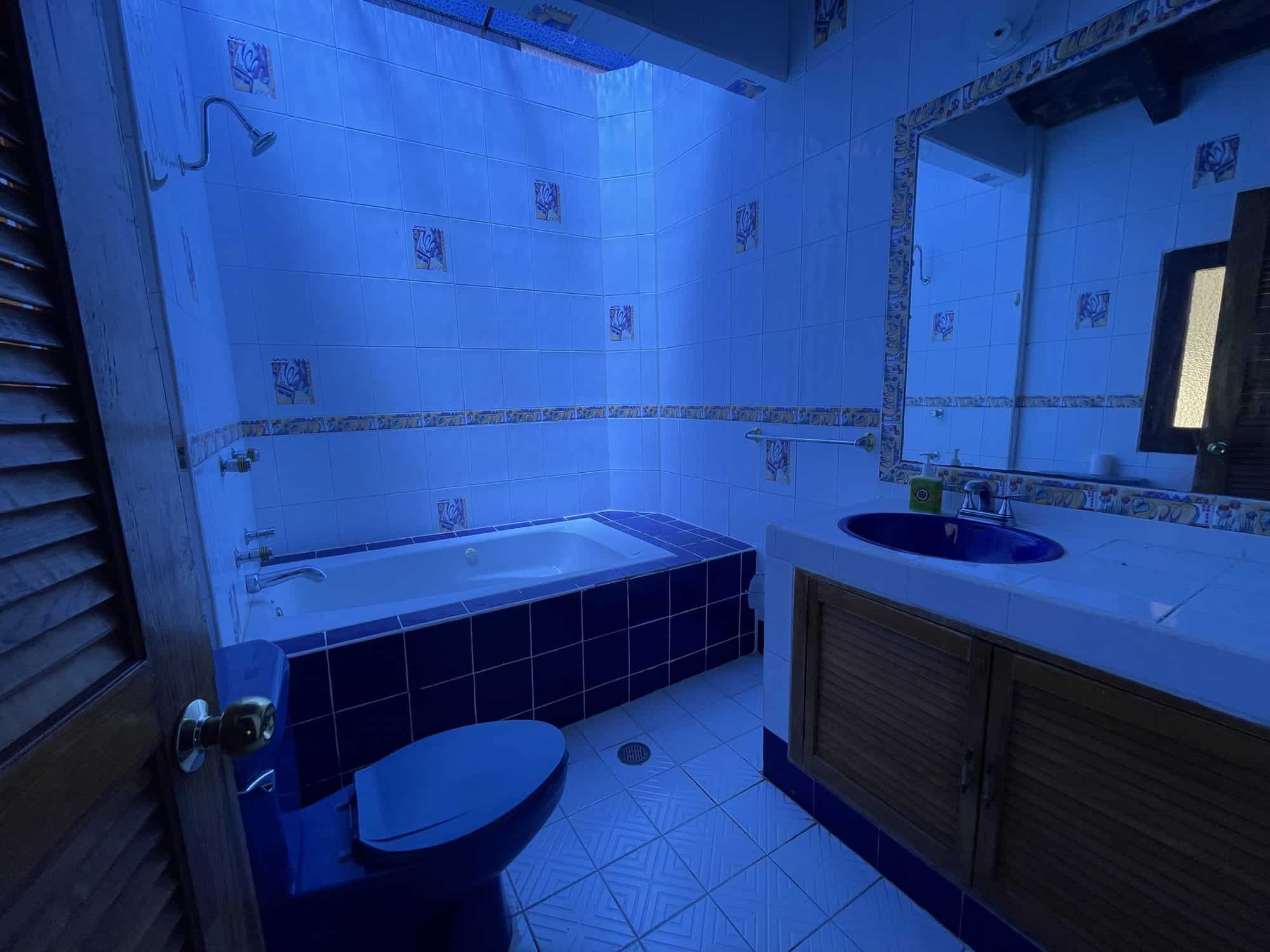 Blue-tiled bathroom with bathtub, toilet, and vanity for sale.