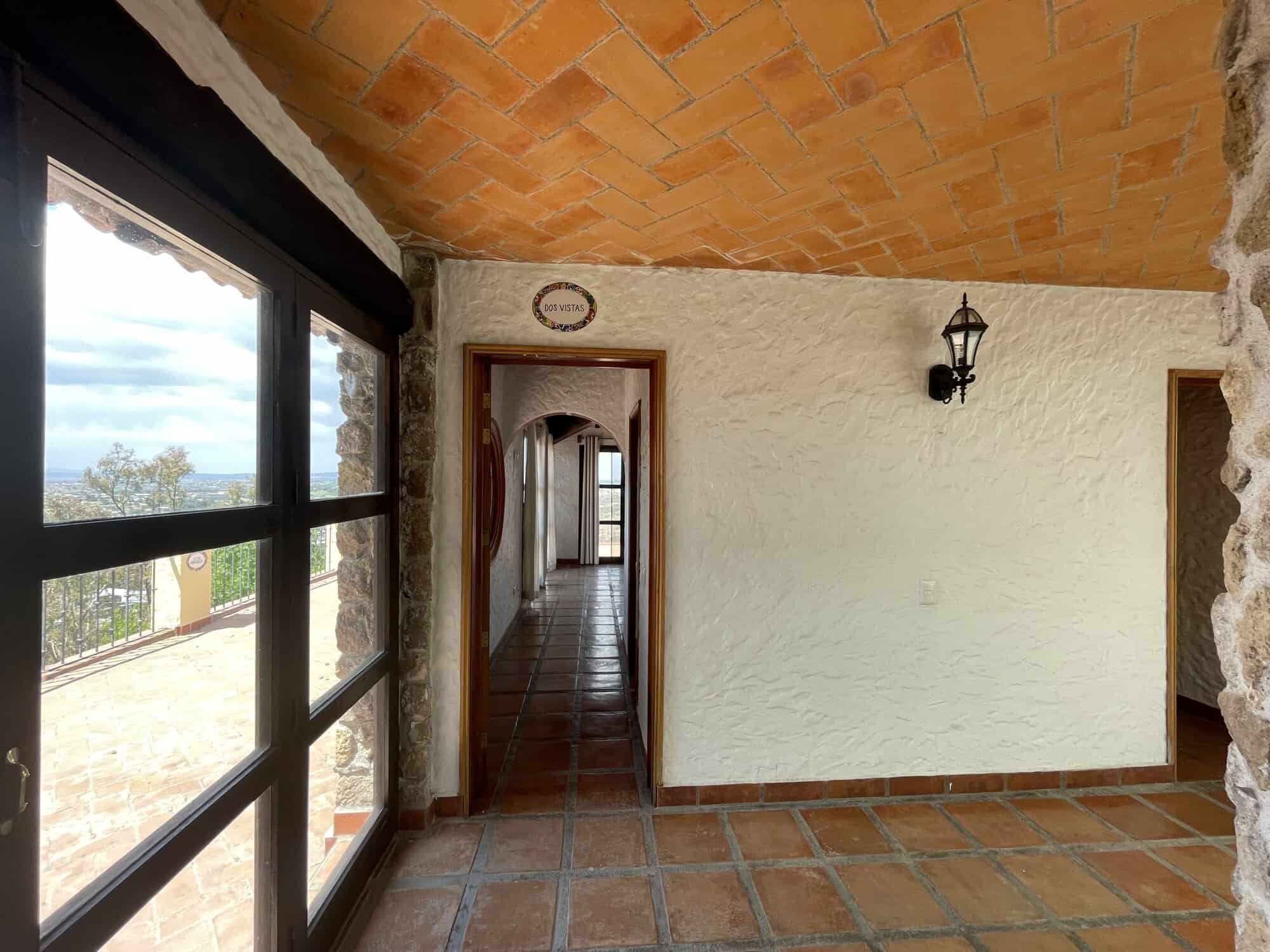 Spacious room featuring terracotta flooring, stone walls, and large windows with scenic views.