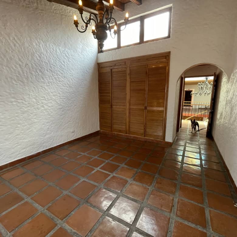 Interior view of a Spanish-style home with terracotta tiled flooring and wooden closet doors.