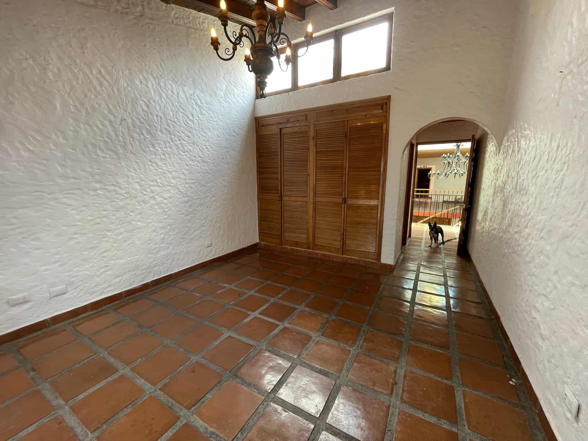 Interior view of a Spanish-style home with terracotta tiled flooring and wooden closet doors.