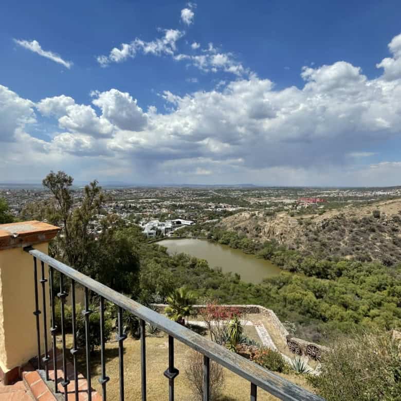 Panoramic view of a river flowing through lush green hills and a distant city skyline under a partly.