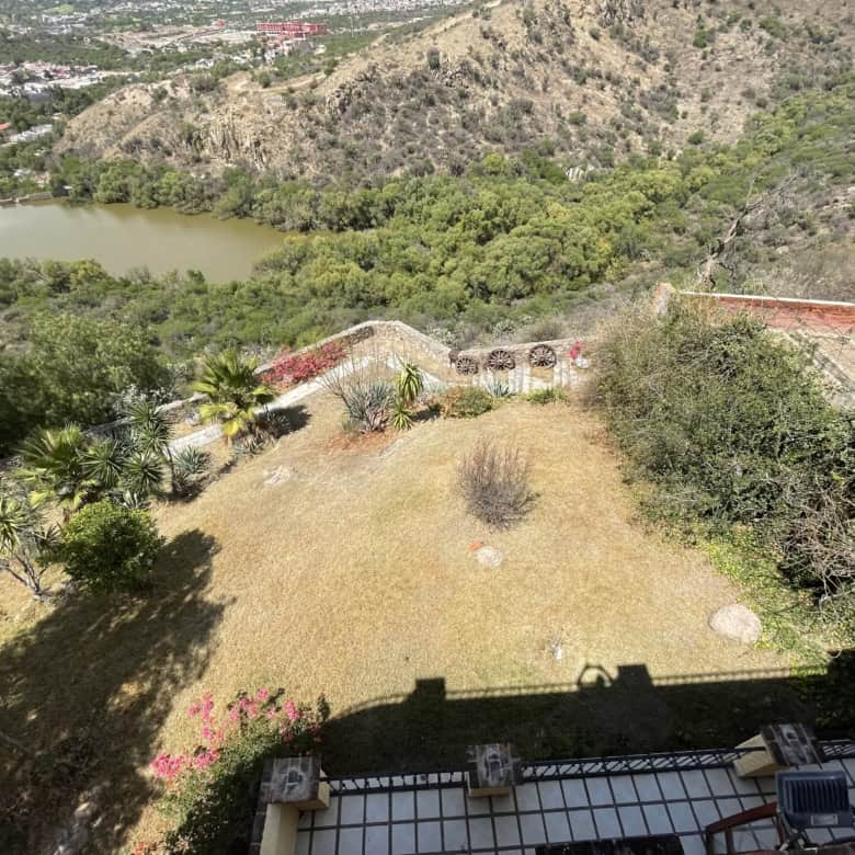 Scenic hillside property overlooking lush greenery and a small lake, ideal for investment or private.