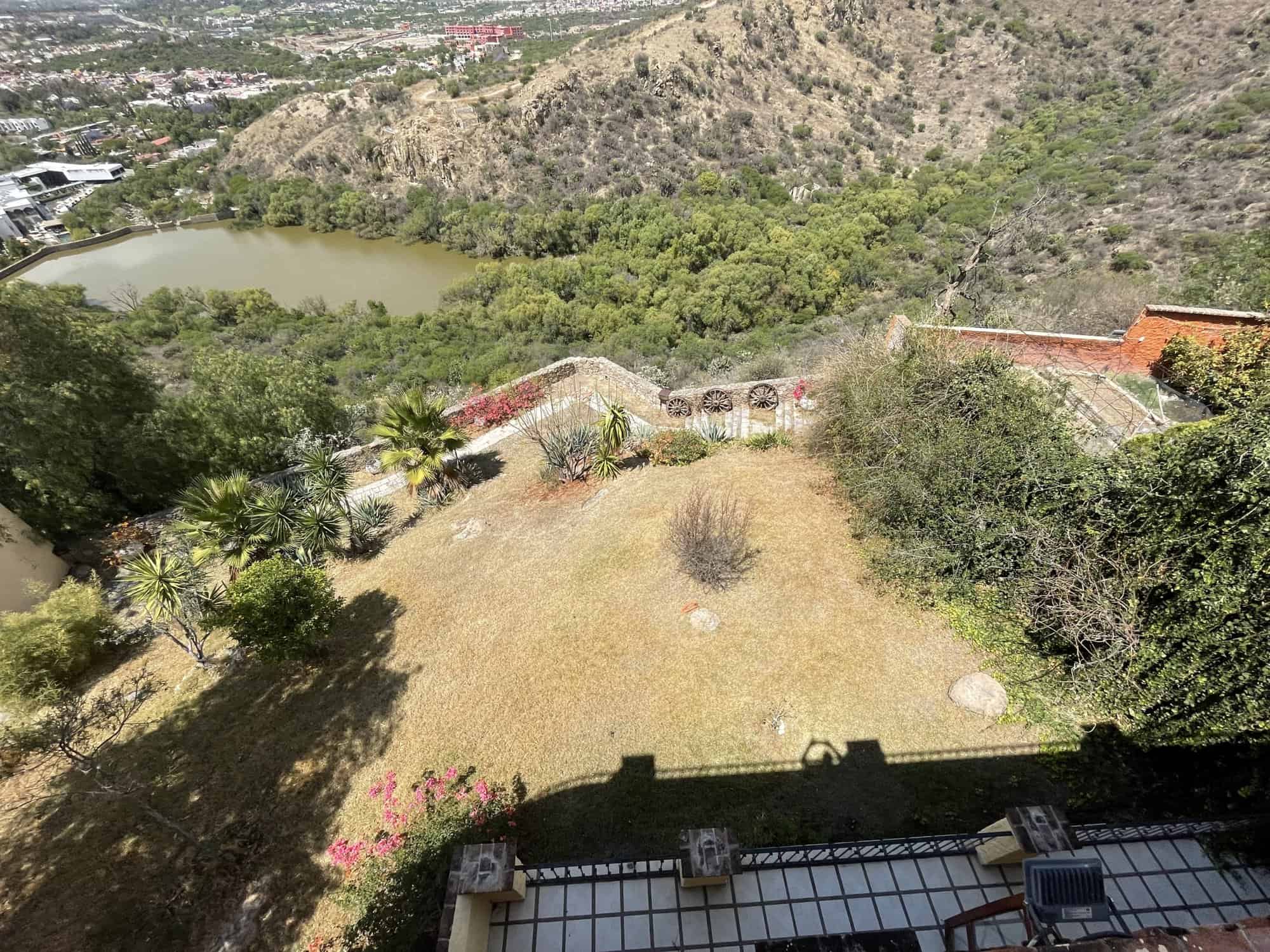 Scenic hillside property overlooking lush greenery and a small lake, ideal for investment or private.