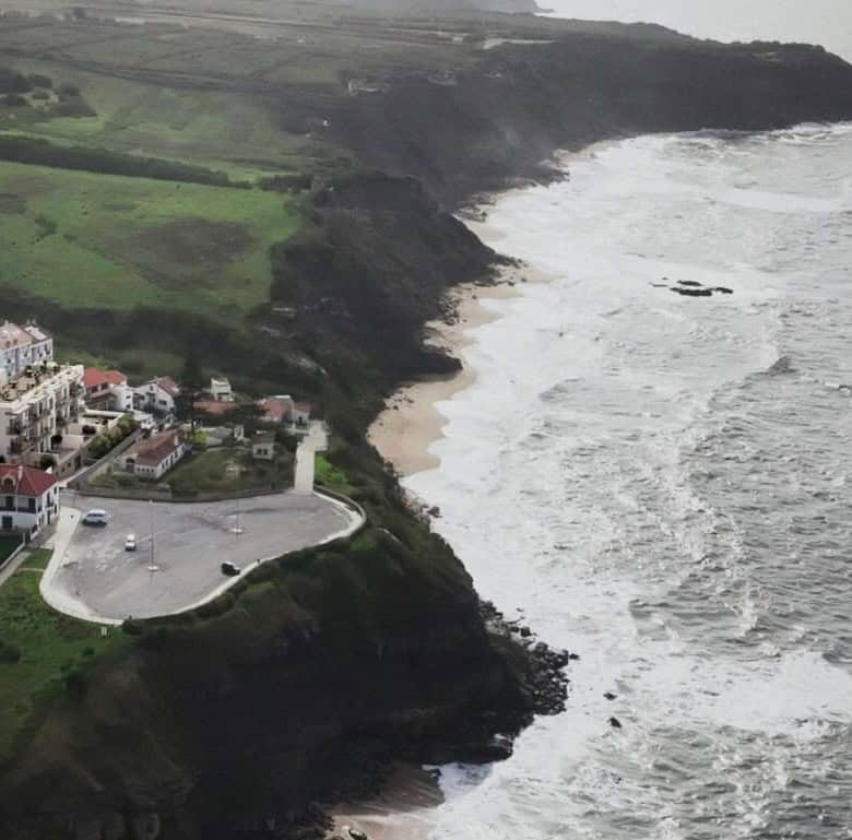 Scenic coastal view of Pôr do Sol near Sao Bernardino, Portugal, showcasing rugged cliffs and ocean.
