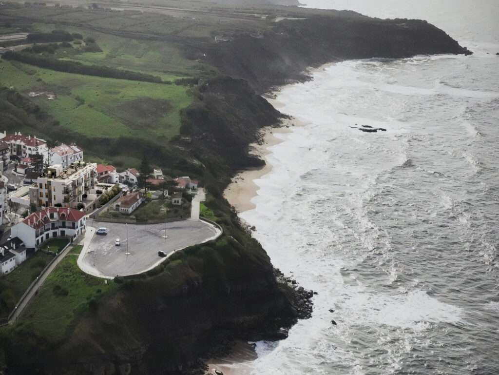 Scenic coastal view of Pôr do Sol near Sao Bernardino, Portugal, showcasing rugged cliffs and ocean.