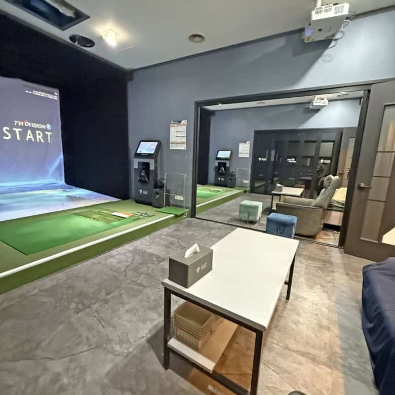 Indoor golf simulation room with advanced screens and putting green.