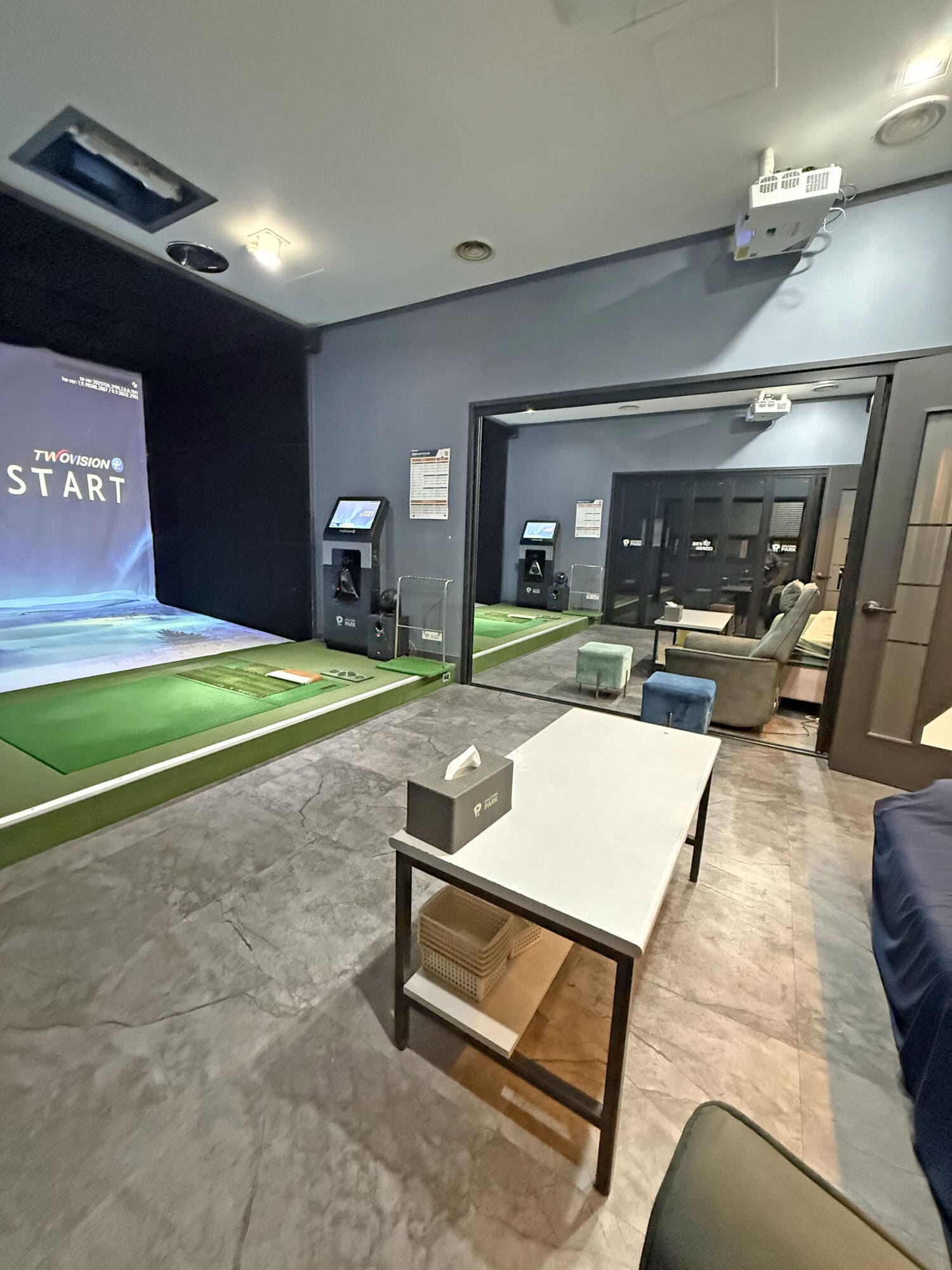 Indoor golf simulation room with advanced screens and putting green.
