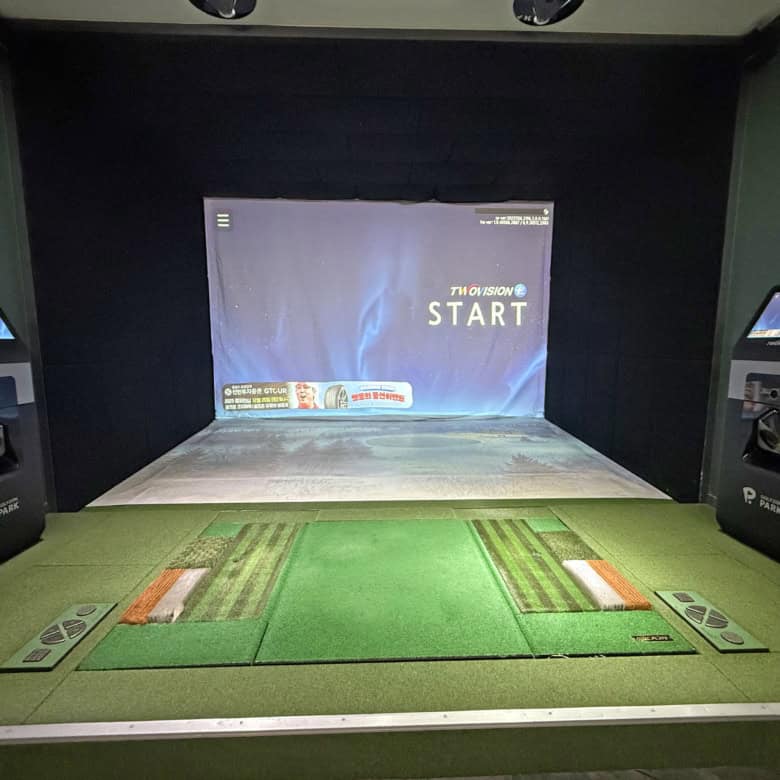 Golf simulator room with screens and golf mats for virtual practice.