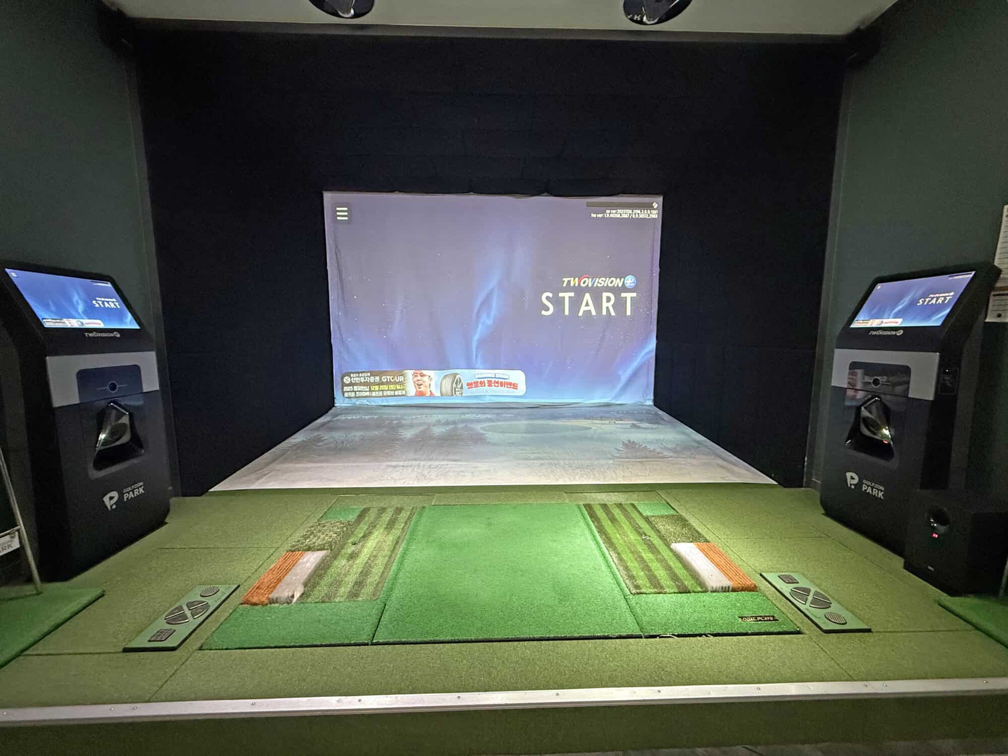 Golf simulator room with screens and golf mats for virtual practice.
