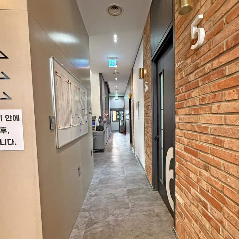 Hotel corridor with brick wall, numbered door 5, and modern lighting fixtures.