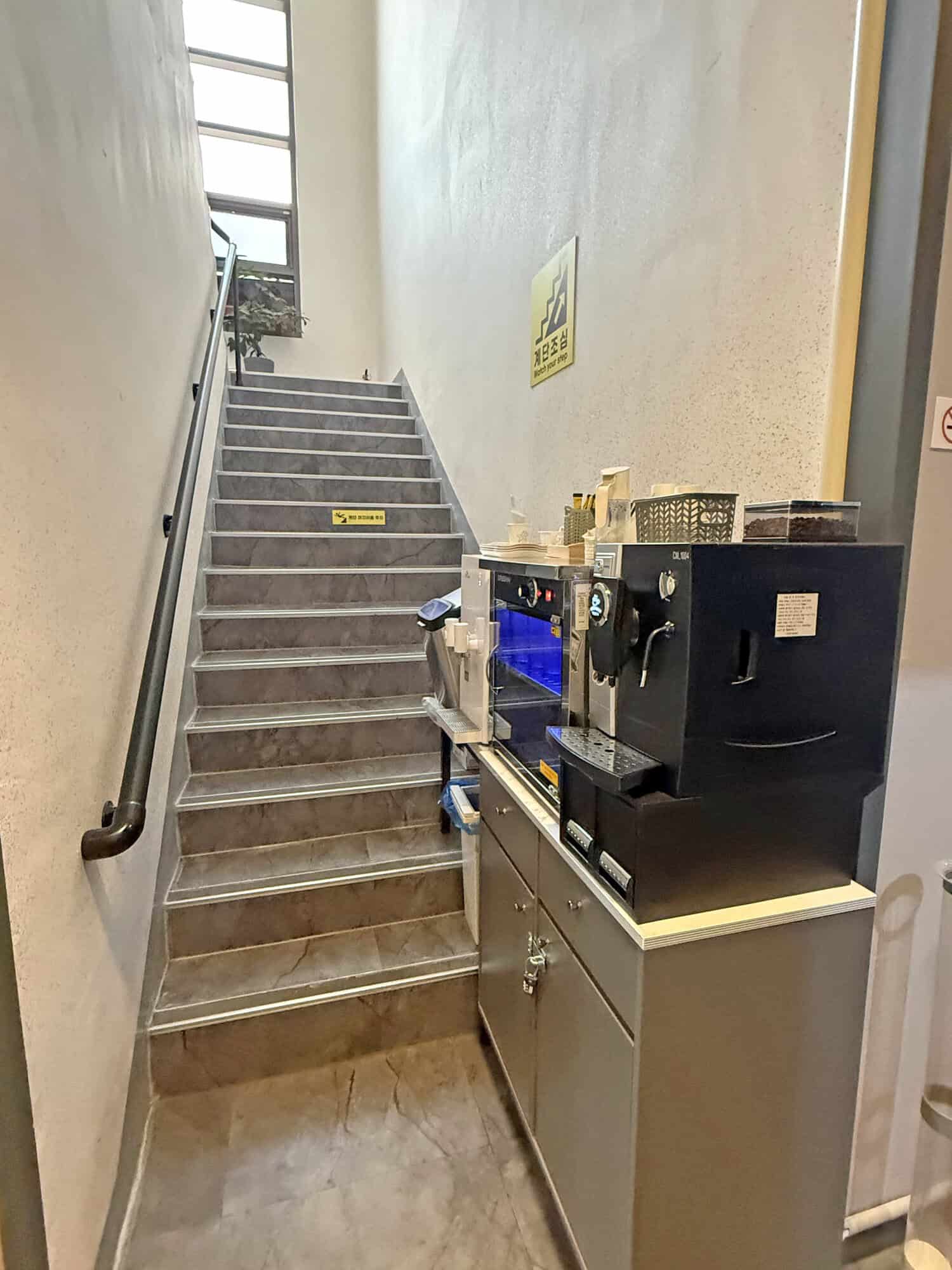 Staircase with handrail and coffee machine in a commercial space.