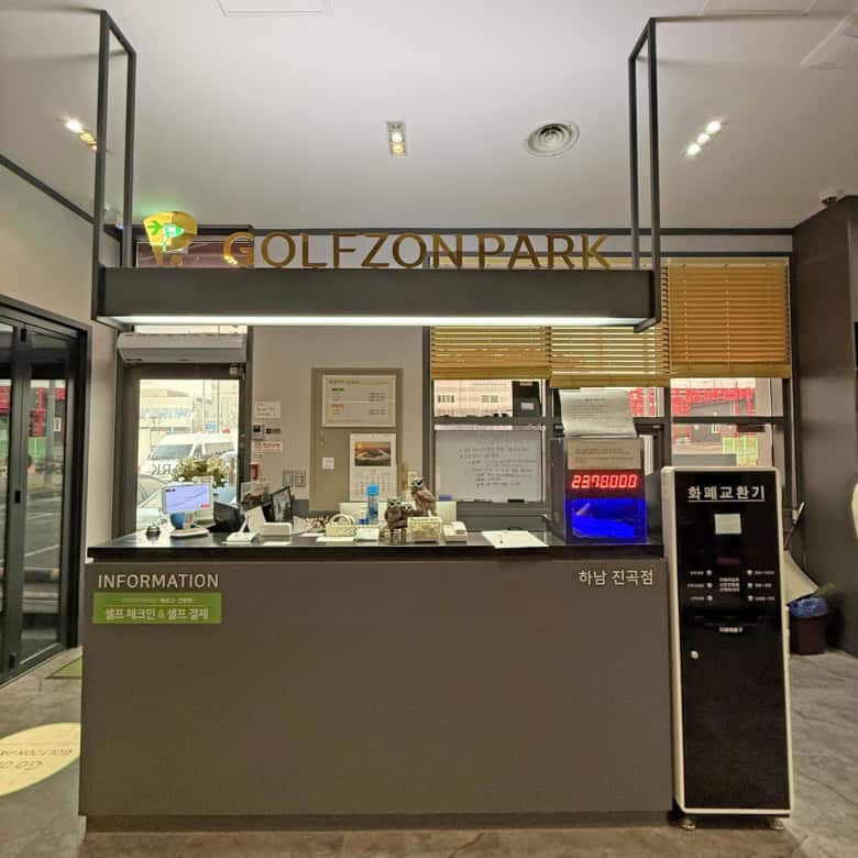 Elegant hotel reception area with check-in counter, currency exchange, and informational displays.