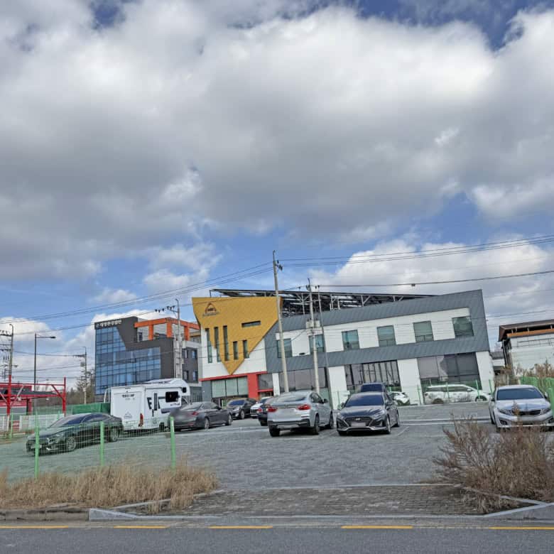 Modern commercial building with colorful geometric design and parking lot.