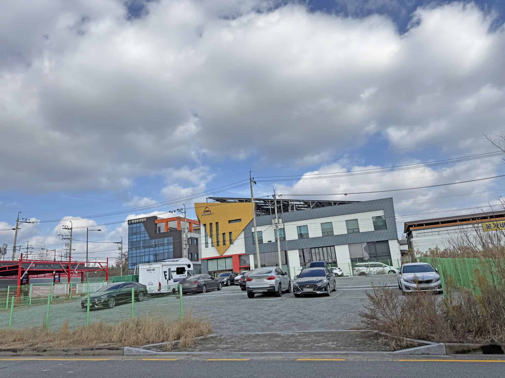 Modern commercial building with colorful geometric design and parking lot.