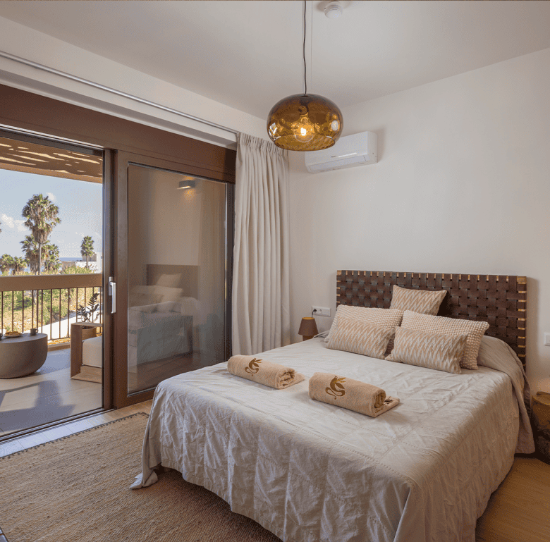Comfortable bedroom at Maleme Residences with balcony views of palm trees and the sea. Perfect for r.