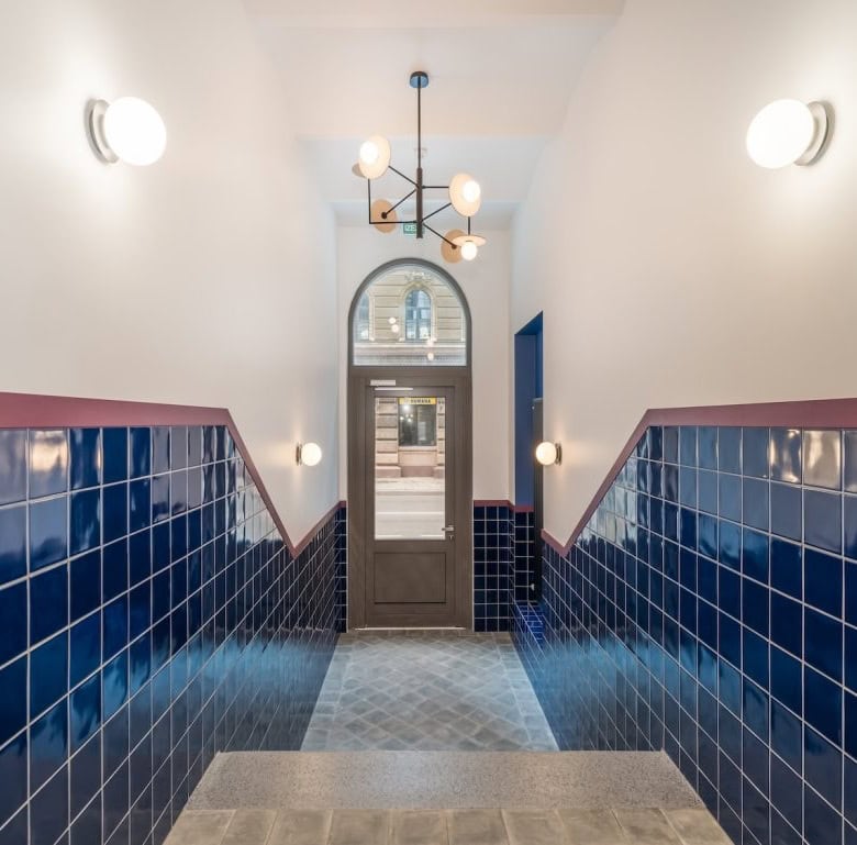 Modern Riga apartment entrance with blue tiled walls and stylish lighting fixtures.