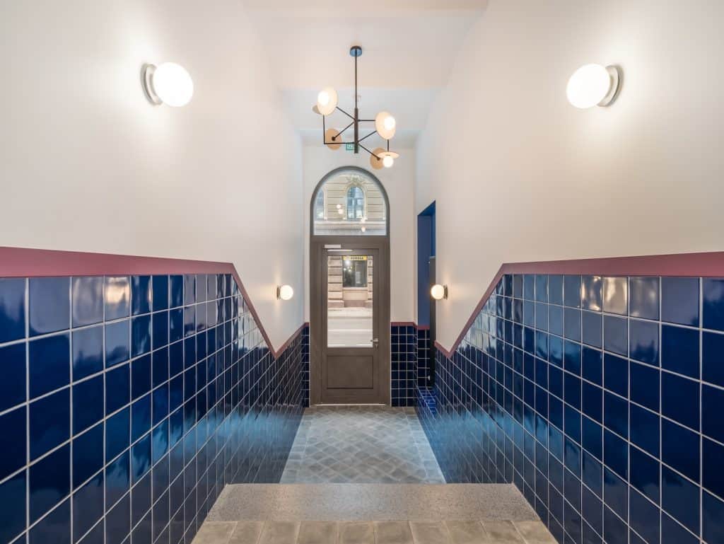 Modern Riga apartment entrance with blue tiled walls and stylish lighting fixtures.