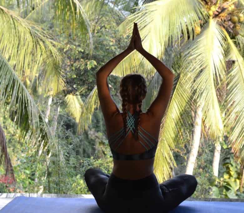 Woman practicing yoga in Ubud Bali amidst lush tropical trees.