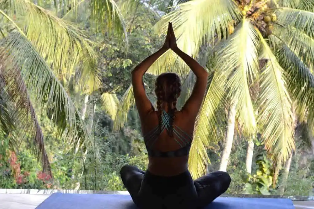 Luxury Bali Villa for Sale Woman practicing yoga in Ubud Bali amidst lush tropical trees.