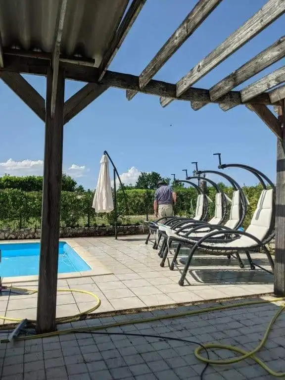 Elegant pool area with sun loungers and shaded seating in a scenic rural setting.