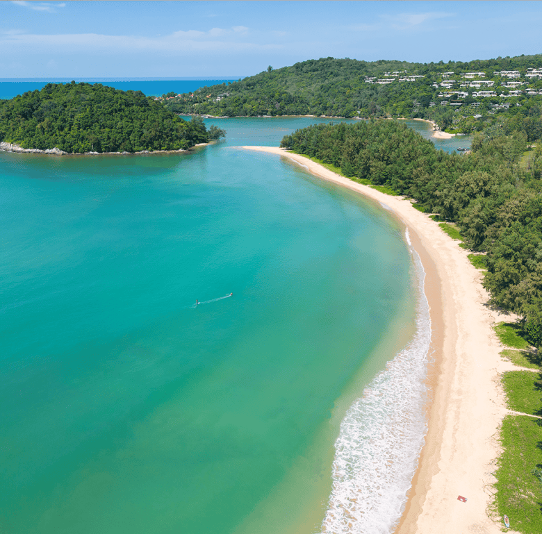 Beach view of Surin Beach with clear turquoise waters and lush green surroundings.