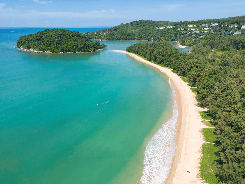 Beach view of Surin Beach with clear turquoise waters and lush green surroundings.