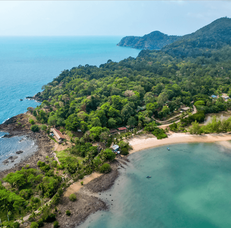 Aerial view of Surin Beach in Phuket, Thailand, showcasing lush greenery, clear waters, and scenic m.