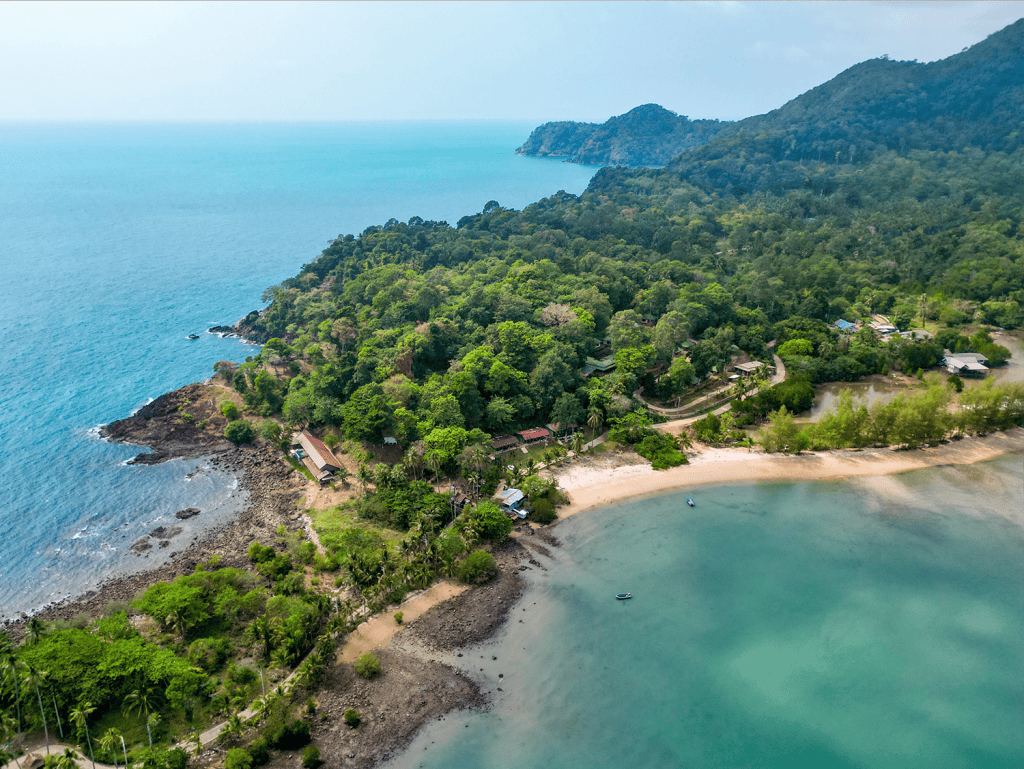 Aerial view of Surin Beach in Phuket, Thailand, showcasing lush greenery, clear waters, and scenic m.