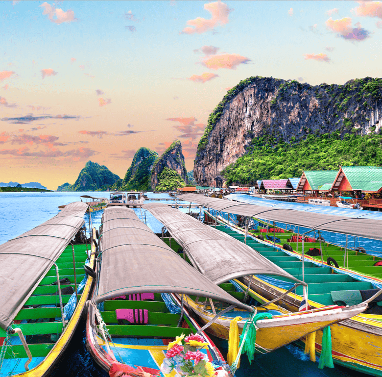 Colorful boats docked at Surin Beach with limestone cliffs in the background, Phuket, Thailand.