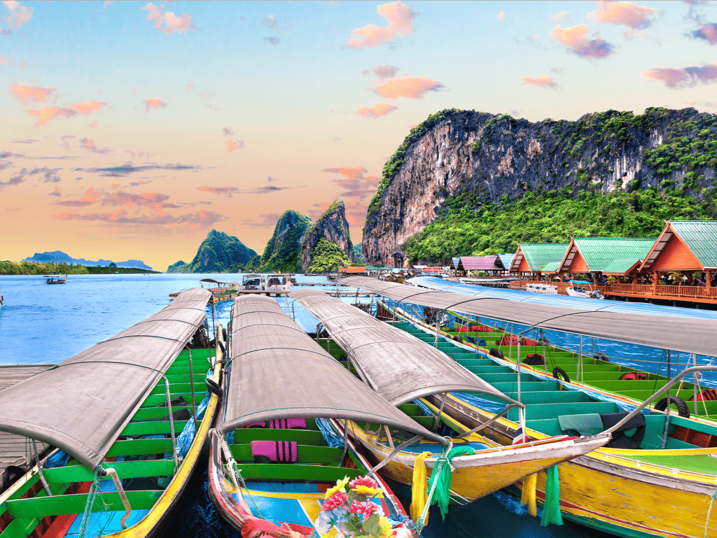 Colorful boats docked at Surin Beach with limestone cliffs in the background, Phuket, Thailand.