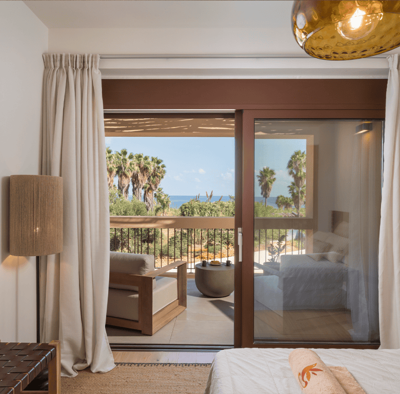 Beautiful bedroom with balcony view of palm trees and ocean in Crete.