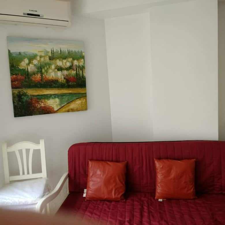 Comfortable living space featuring a red sofa, decorative pillows, and wall art in a bright, airy ro.