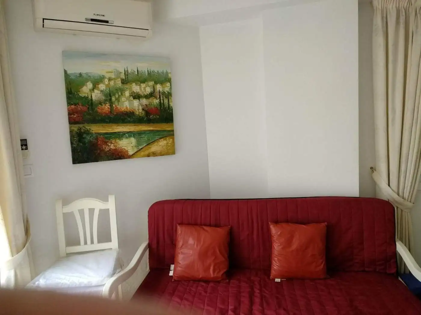 Comfortable living space featuring a red sofa, decorative pillows, and wall art in a bright, airy ro.