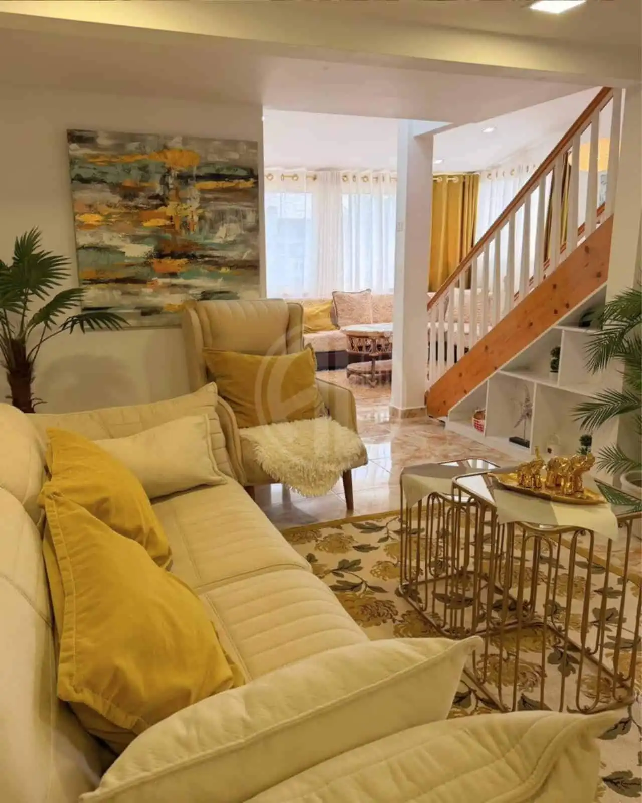 Bright living room with beige sofas, artwork, and gold accents.