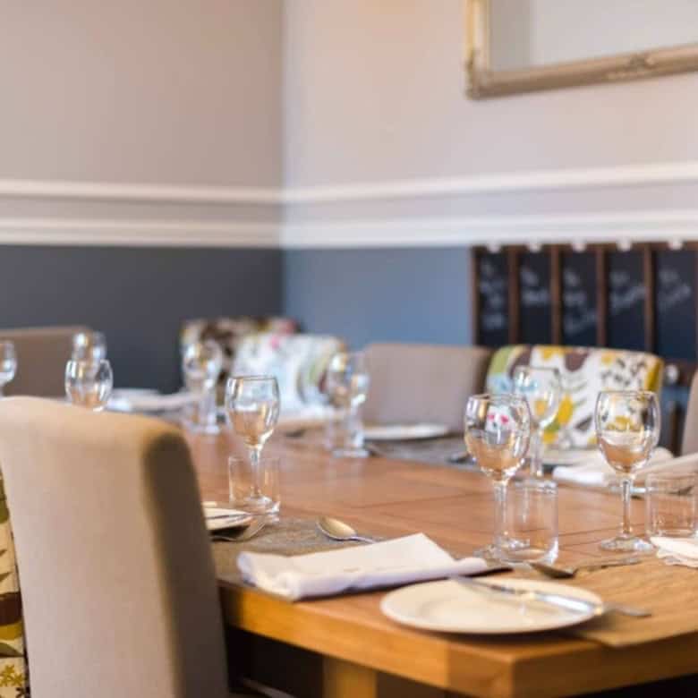 Elegant dining room with a wooden table, glassware, and floral-patterned chairs for a sophisticated.